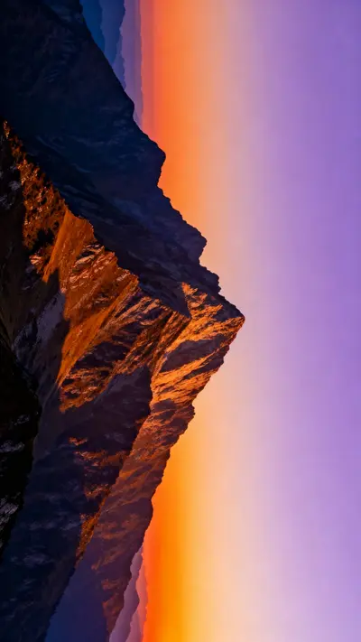 A scenic sunset over mountain peaks with a sky filled with orange and purple clouds.